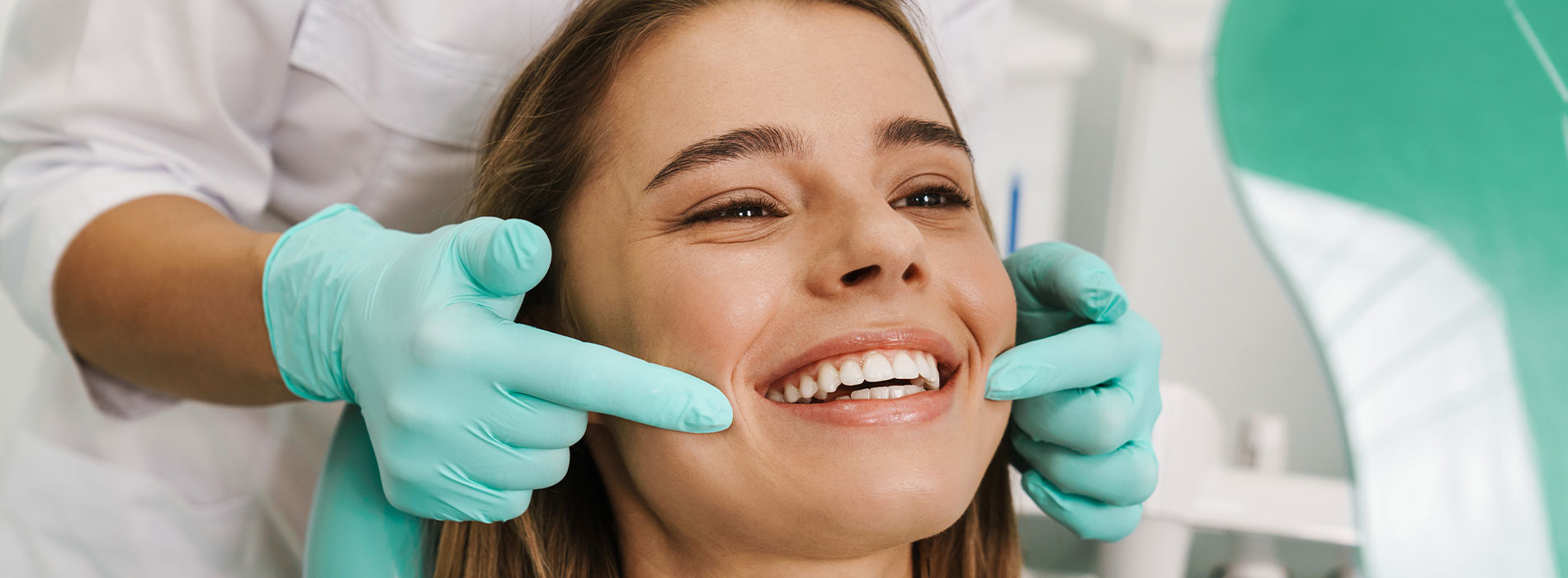 The image shows a person receiving dental care, with a dentist performing a procedure on their teeth while they are seated in a dental chair.