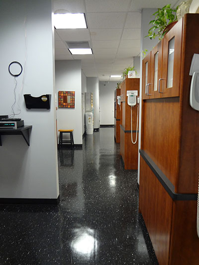 The image shows an interior hallway with dark flooring, a series of partitions with doors, and a white wall on one side.